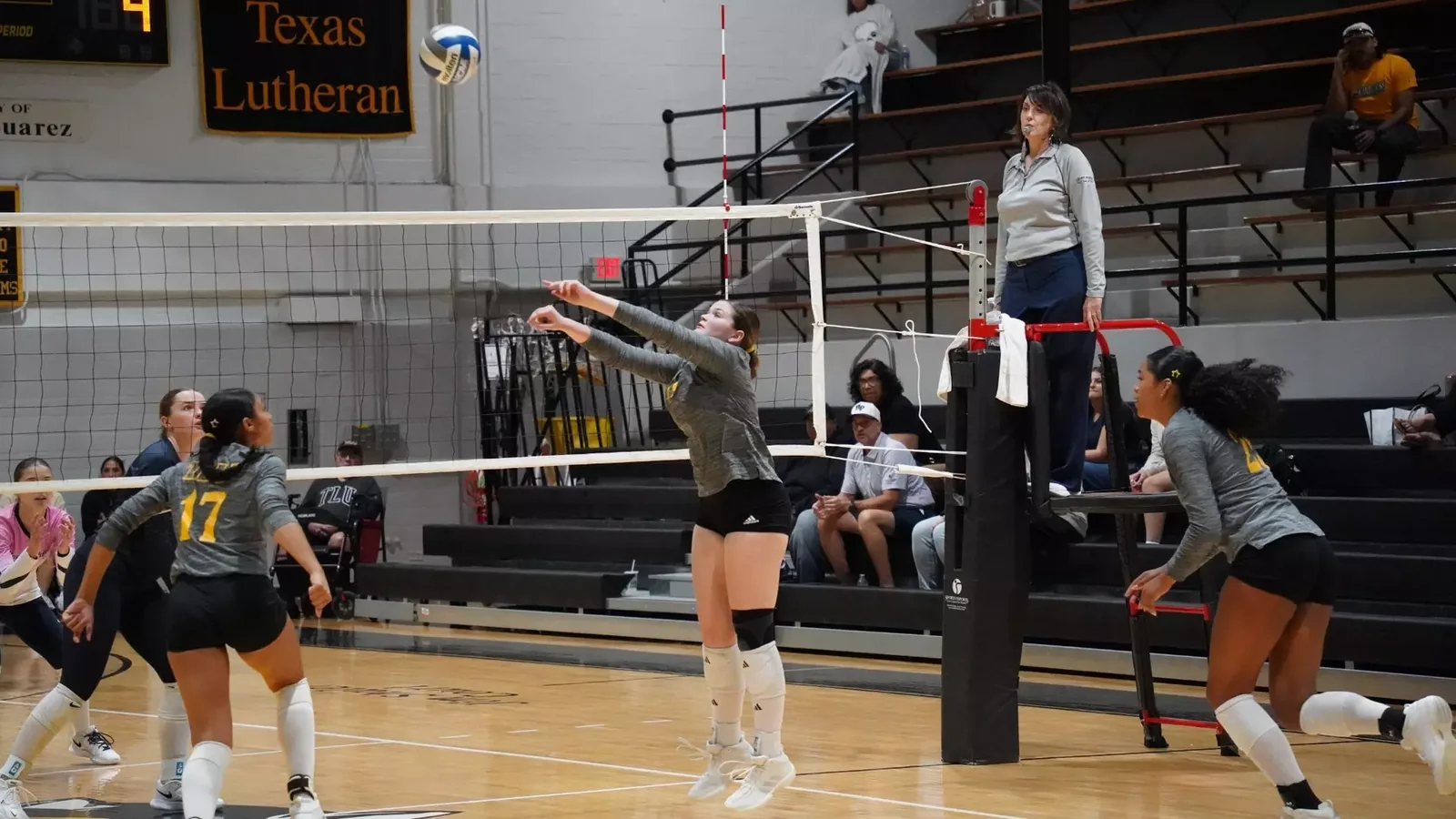 Texas Lutheran volleyball player extending her forearms toward the ball while teammates watch