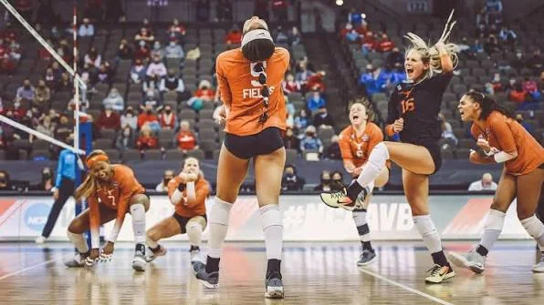 Texas volleyball players in orange and a black-jersey teammate reacting on court