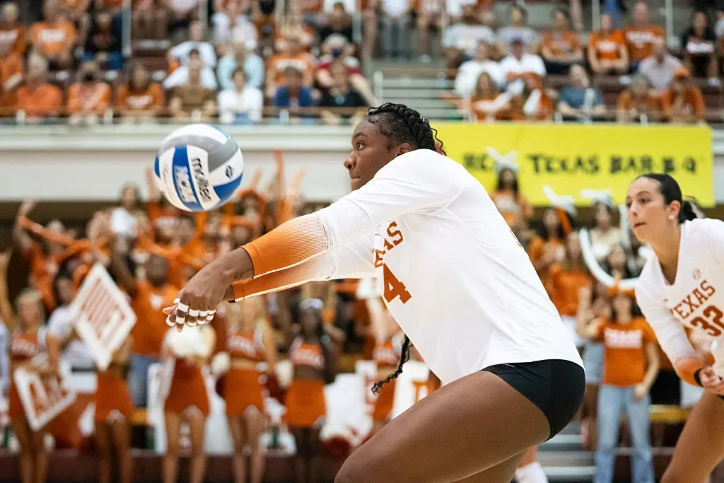 Texas volleyball player in white receiving the ball with a forearm passing platform